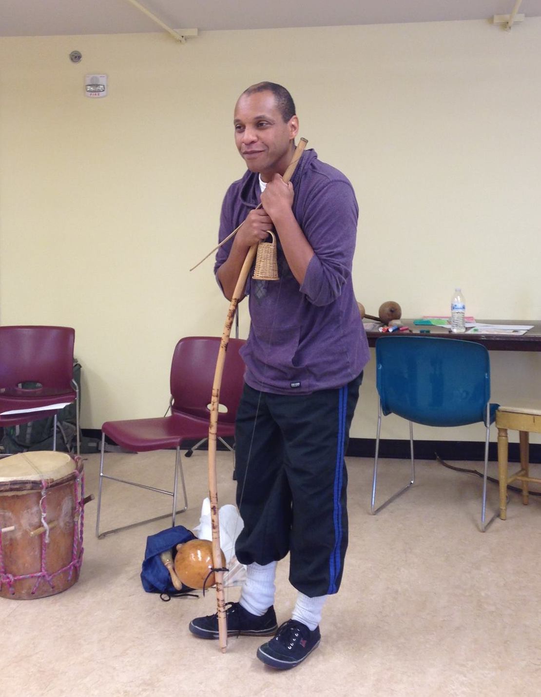 Silvio happily leans on the Berimbau with a soft grin