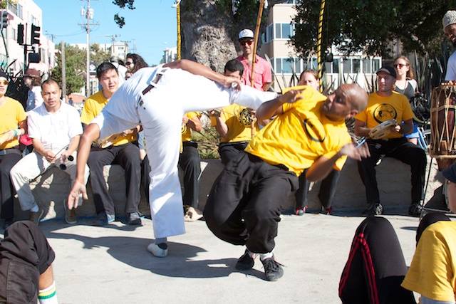 Silvio bends sideways while squatting to dodge a capoeira kick