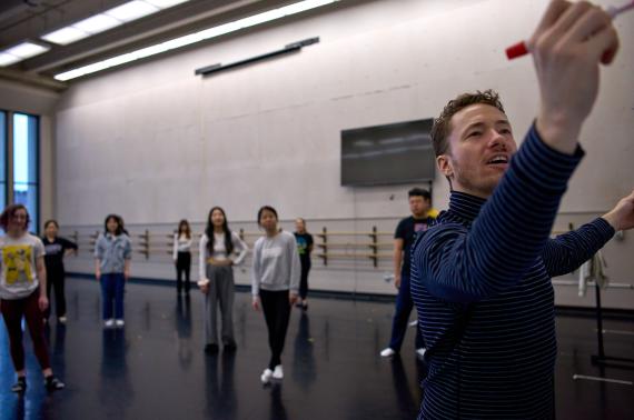 Derek Crescenti writing on a white board in the Meany Hall dance studio 