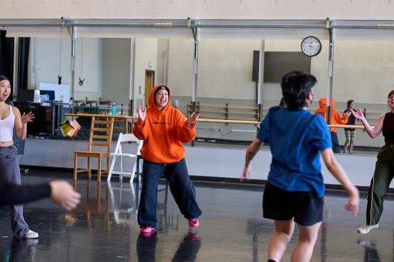 Annie Franklin teaching dance class wearing a bright orange hoodie. 