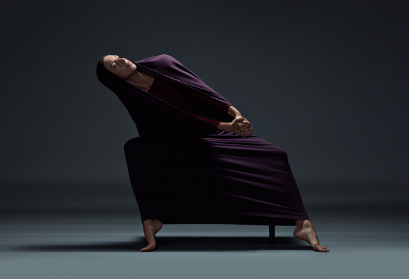dancer in purple cloth leans over