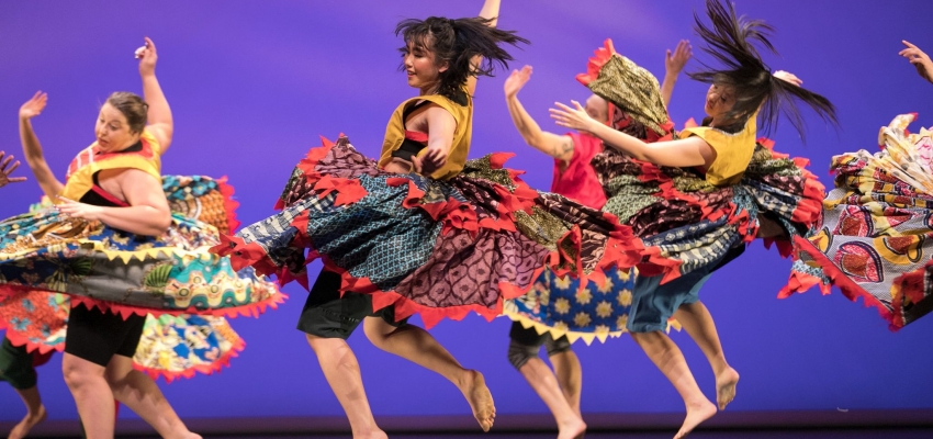 students performing African dance in big colorful skirts 