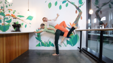 Juliet balances laying on top of Cristian who is tilted and standing on one leg 