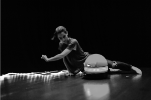 A woman dances on the floor with a small robot
