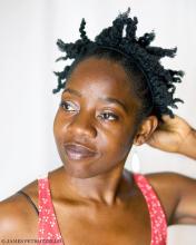 Rujeko Dumbutshena touches the back of her head