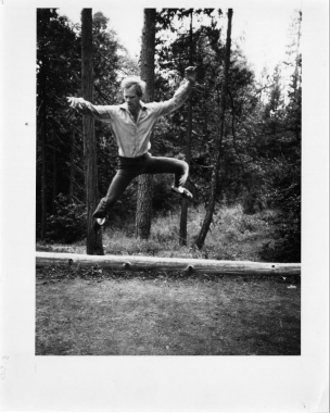 Douglas Dunn jumping high infront of tree trunks 