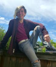 Drew sitting on a fence with his arm resting on his knee