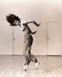 Trisha Brown flings her hair forward and her arms behind her