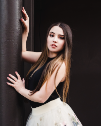 Heather leans against a pole in pointe shoes and a floral tutu