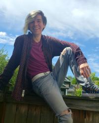 Drew sitting on a fence with his arm resting on his knee