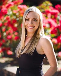 Courtney Porter smiles in front of red flowers