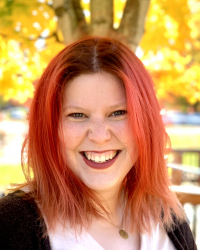 Tori Siddall smiles in front of yellow trees.