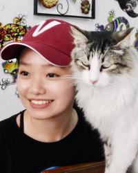 Victoria Zhu in a red cap with her cat