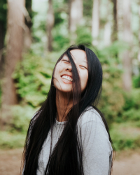 Anna lee shrugs and smiles with some hair blowing in her face 