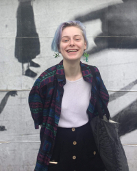 Kelly smiles in front of a wall 