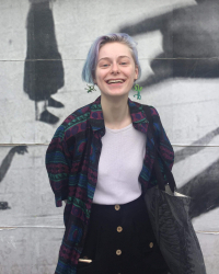 Kelly smiles in front of a wall