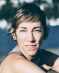 a white woman in her mid-forties with blue eyes, short hair, in a grey tank top 