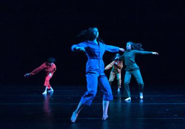 dancers dressed in bright colored jumpsuits in motion 