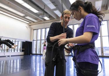 Rachael Lincoln helps a student secure their rope and harness in the dance studio 