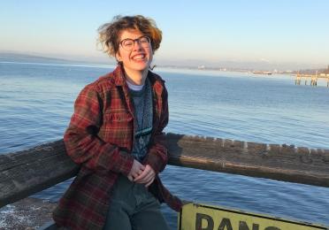 Andy smiles in front of water by a danger sign 