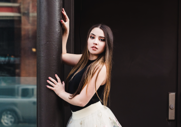 Heather leans against a pole in pointe shoes and a floral tutu 