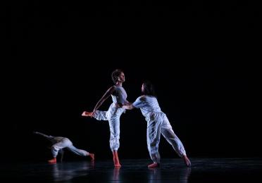 Madison stands on one leg being supported by another dancer. 
