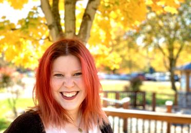 Tori Siddall smiles in front of yellow trees. 