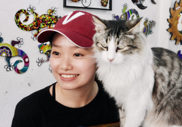 Victoria Zhu in a red cap with her cat