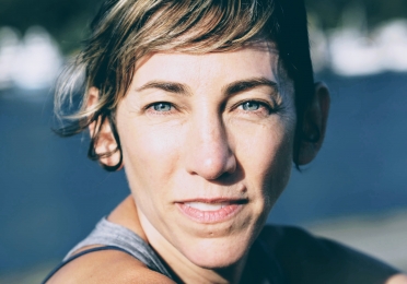 a white woman in her mid-forties with blue eyes, short hair, in a grey tank top 