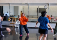 Annie Franklin teaching dance class wearing a bright orange hoodie. 