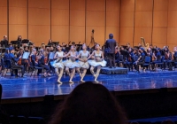 Four dancers performing "dance of the little swans" in front of the orchestra on Meany Hall stage 