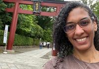 Christina Sunardi smiles in front of a Japanese "torii" gate 