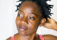 Rujeko Dumbutshena touches the back of her head