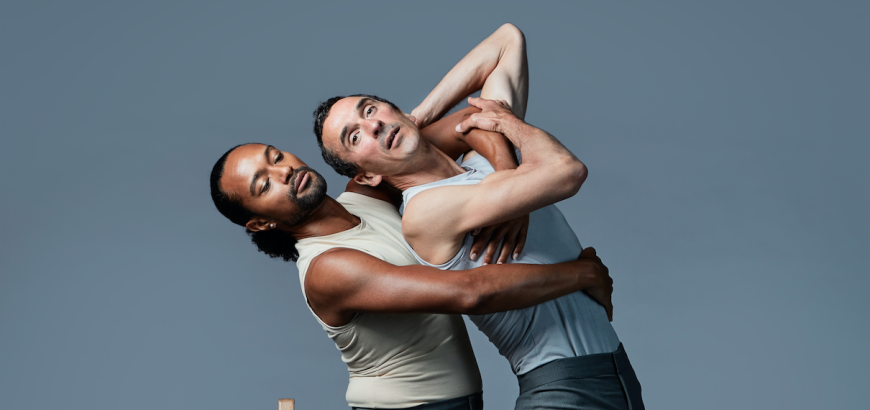 dancers embrace while bending backwards over a chair