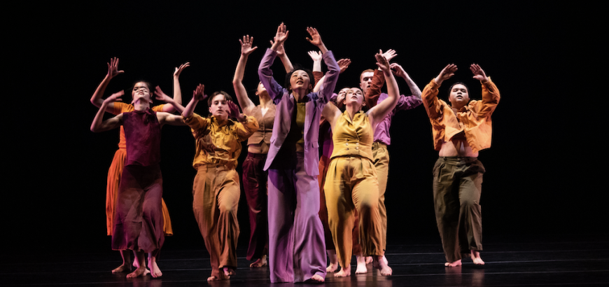 UW Dancers in colorful clothing on stage with their hands up