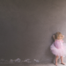 A little girl in ballet clothing standing at a wall 