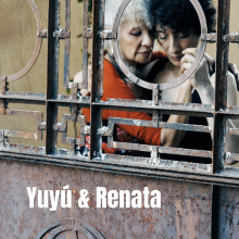 faces of two women dancing tango as seen through ornate old metal fence