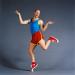 Bald man in bright athletic clothing humorously balances on one toe. 