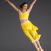 Lady in yellow jumps with arms in wide 'V' shape and legs straight and together. 